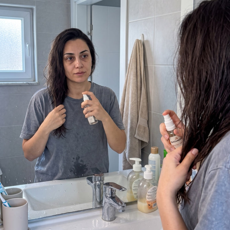 Aynada saçına serum uygulayan kadın