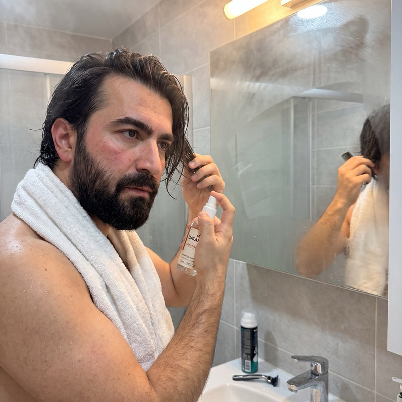 Duş sonrası saçına serum uygulayan erkek